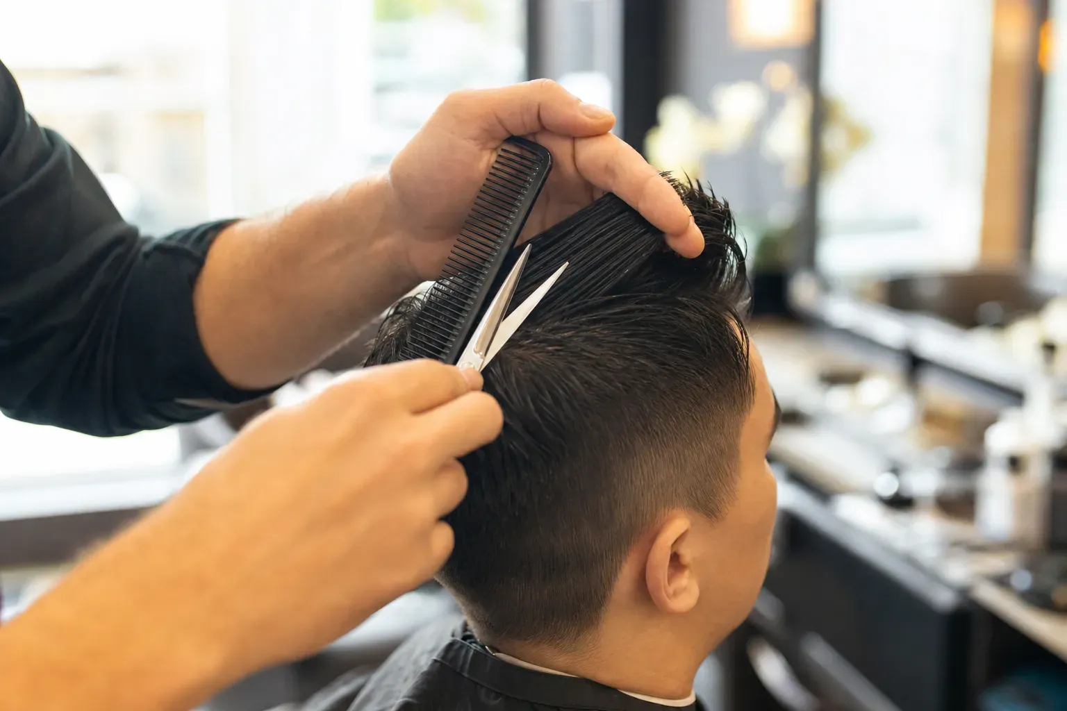 Master barber shaping a scissor cut at a Camp Ave Barbershop station